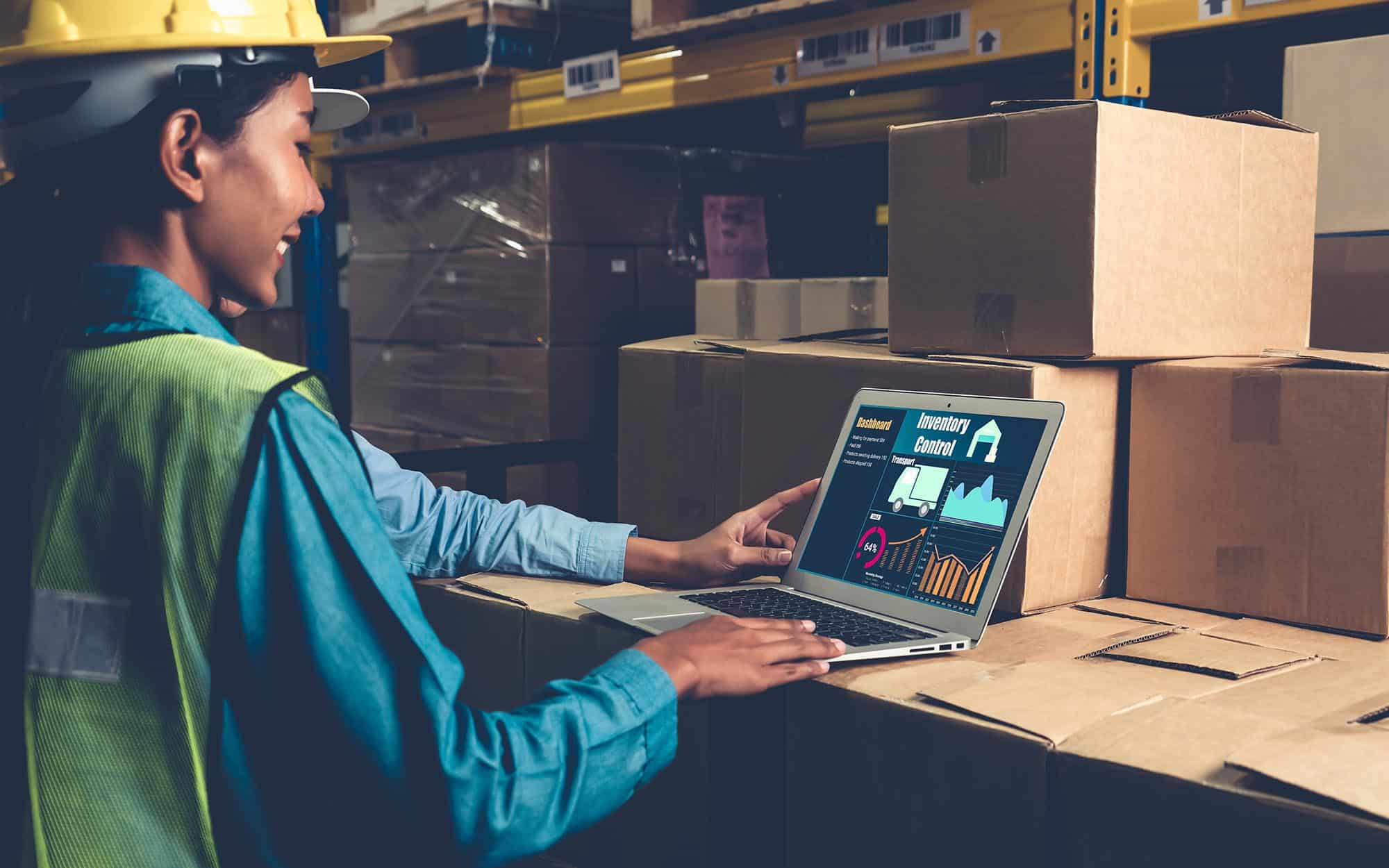Factory Worker Looking At Computer With Real Time Inventory | FW Logistics